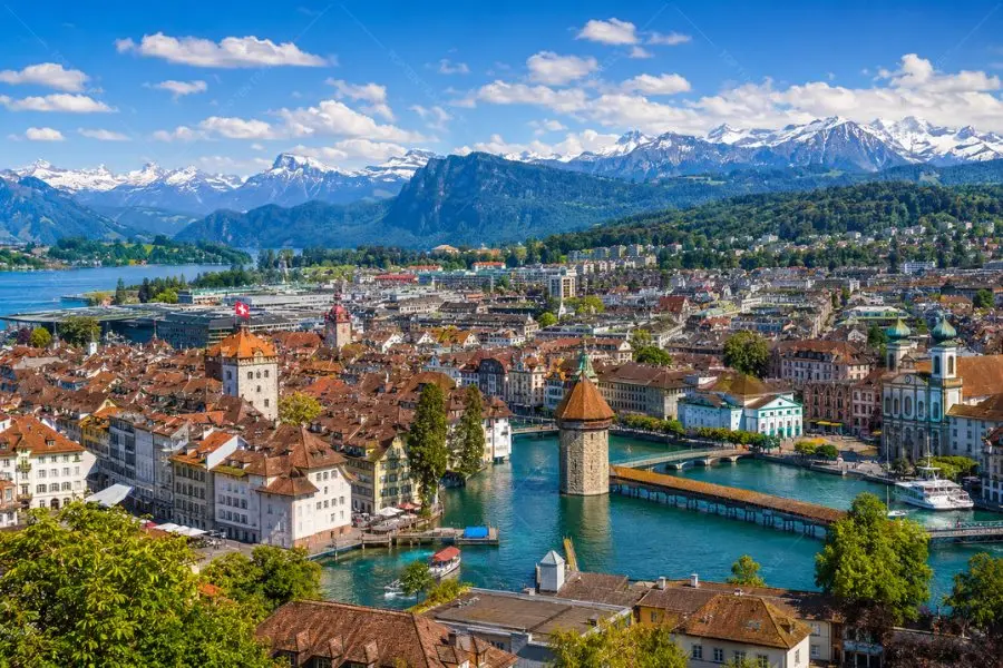 Thị trấn Lucerne mùa hè nổi bật với cầu Chapel Bridge, hồ Lucerne trong xanh và dãy Alps hùng vĩ phía sau.