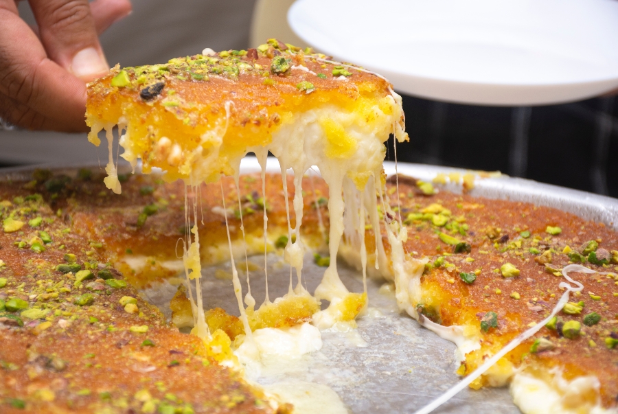 Knafeh được làm từ lớp phô mai kéo sợi béo mềm đặt giữa hai lớp bột sợi mỏng chiên giòn