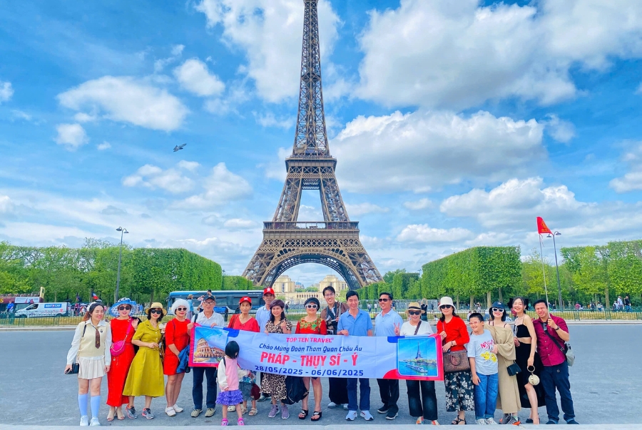 Đoàn khách đi tour Châu Âu chụp ảnh bên cạnh tháp Eiffel