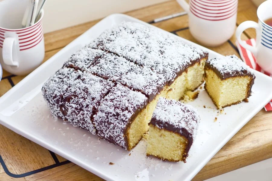 Lamington được làm từ cốt Gato xốp mềm nhúng trong sôcôla ấm nóng và phủ thêm một lớp cơm dừa sấy bên ngoài